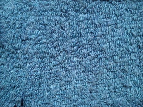 Close-up of woolen fabric and knitting in blue. Thick weave of terry thick threads. Shaggy, uneven surface.
