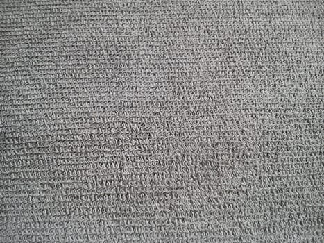Gray cotton or linen. Separate threads and weaves are noticeable. Gray nondescript background. Sewing universal material. Fine knit machine knitting.