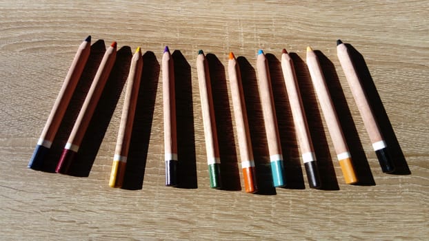 On a wooden table are wooden thick colored pencils