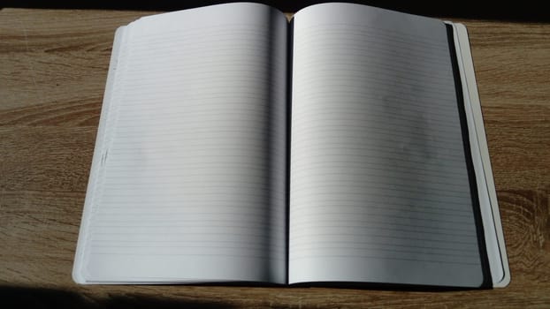 U-turn notebook with blank white pages. Harsh natural sunlight