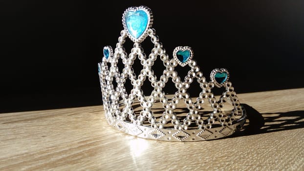 silver crown with a blue stone shines in side lighting