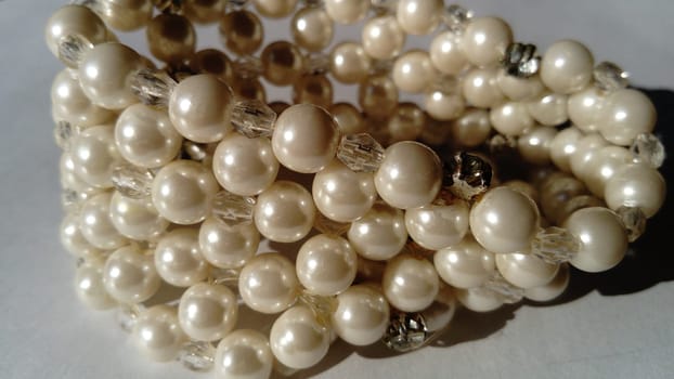 Women's bracelet made of white pearls. Soft light. Feminine design. White background.