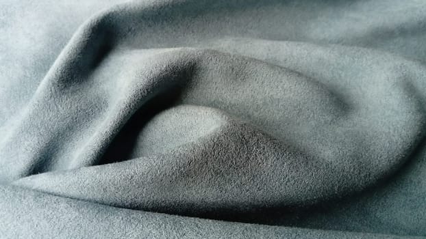 Close-up of velvety fabric for curtains of gray and blue color pleated with the play of chiaroscuro