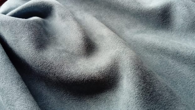 close-up of velvety thick fabric for curtains of gray and blue color pleated with the play of chiaroscuro