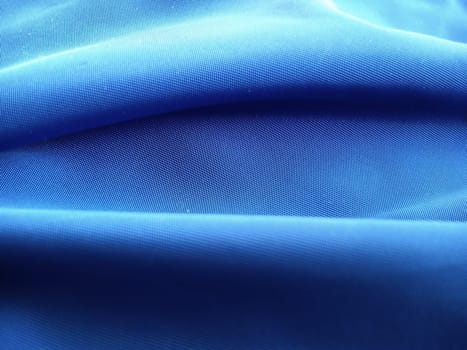 Blue fabric at close range, laid in horizontal waves. Abstract image in shades of blue