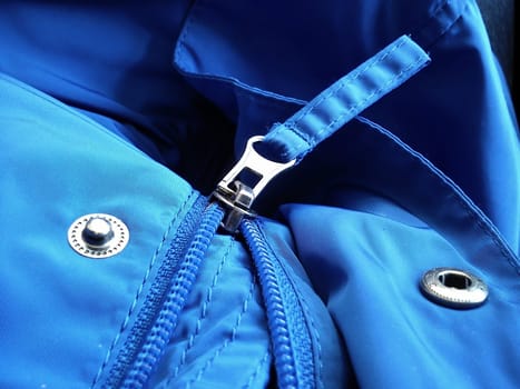 Half-open sewing lock on a blue synthetic fabric jacket. Open sewing buttons.
