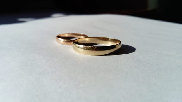 gold jewelry in the form of two golden wedding rings on a white background