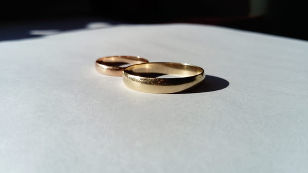 gold jewelry in the form of two golden wedding rings on a white background