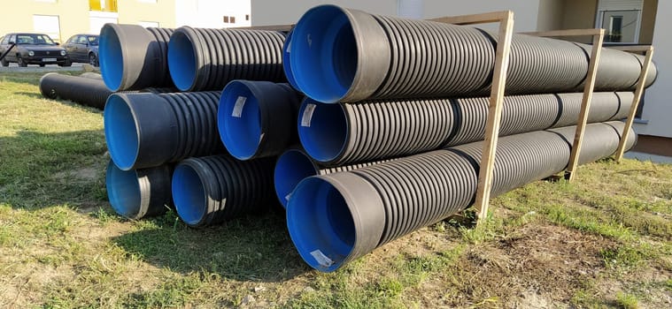 Sremska Mitrovica, Serbia, 23 August 2020. Metal corrugated pipes, blue inside. Plumbing or heating pipes lie on the ground next to a residential building. Corrugated metal.