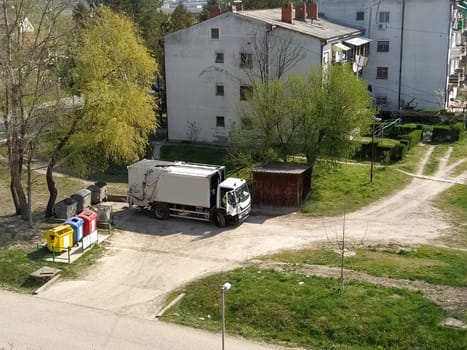 Sremska Mitrovica, Serbia, June 1, 2020. Garbage truck on the city street. Municipal and city services. Waste management and disposal. Car pulling up at the trash cans.
