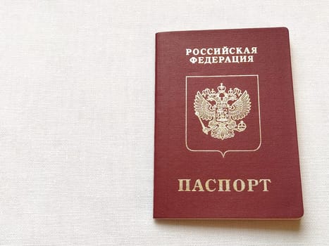Passport of a citizen of the Russian Federation. International passport for travel and border crossing. Burgundy document cover with embossed gold letters. White background from textile.