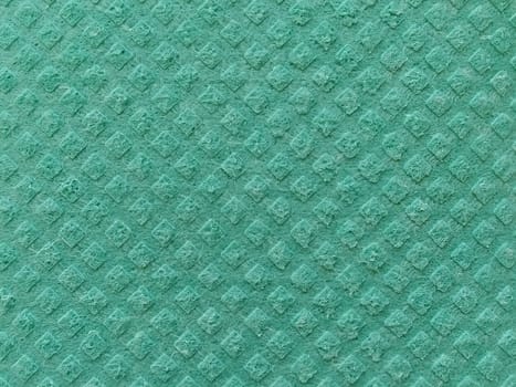 Close-up of fabric with raised print. Convex diamonds on green microfiber or dishwashing sponge. Background and free space for text.