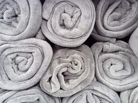Gray blankets, rolled up and lying on a shelf in a store. Scandinavian lifestyle. Interior decor elements. Warm blankets.