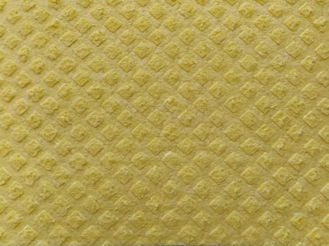 Close-up of fabric with embossed convex print. Bulging diamonds on yellow microfiber or dishwashing sponge. Background and free space for text.