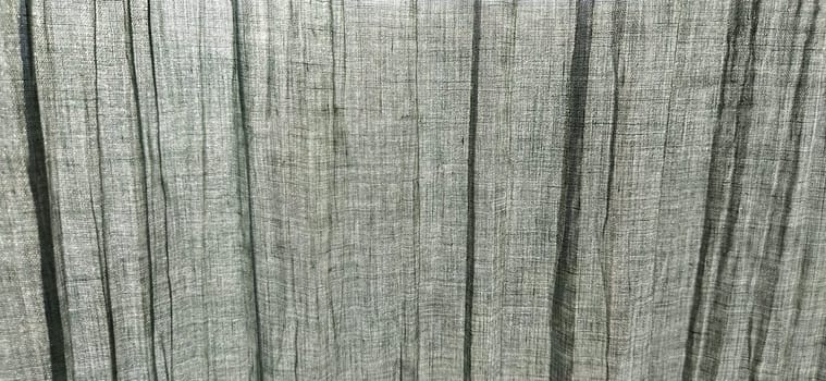 Gray pleated fabric or crumpled textile closeup. Light translucent curtains or tulle in the Scandinavian style. Soft focus. Pastel colors on the fabric.