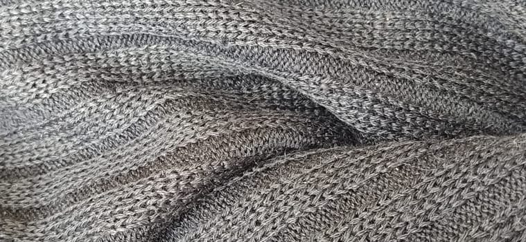 Knitted product. Black and white photo. Loops and texture of a knitted sweater close-up. Weaving woolen and acrylic threads. Industrial production of casual wear. Monochrome. Blurred photo as a banner