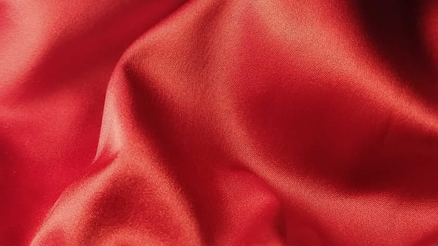 Closeup of ripples in red silk or satin fabric. Red Fabric cloth textured background in minimal modern style. Backdrop. Background for celebration, ceremony, event invitation card, advertising poster.