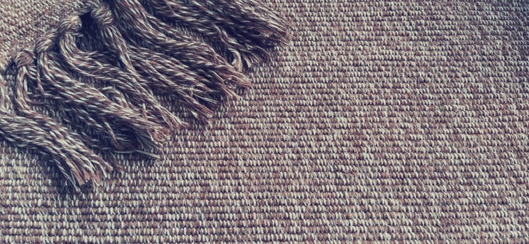 Woven fabric with tassels. Coarse weaving cotton. Floor mat. Beige, white and wrinkled threads in weaving. Woolen or acrylic material