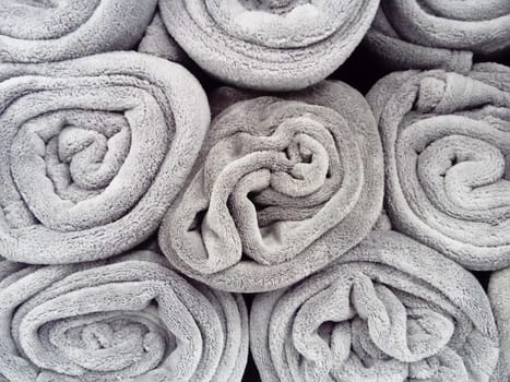 Gray blankets, rolled up and lying on a shelf in a store. Scandinavian lifestyle. Interior decor elements. Warm blankets.