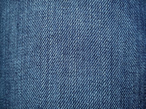 Blue denim. Texture of cotton coarse material. A fragment of a natural rag indigo. Vertical furrows, dark and light threads, individual stitches are noticeable.