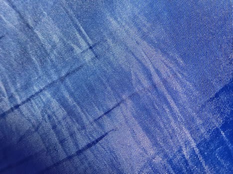 Blue silk lining. Close-up. A piece of fabric on curtains or a raincoat. Abstract macro image. Weaving thin threads.