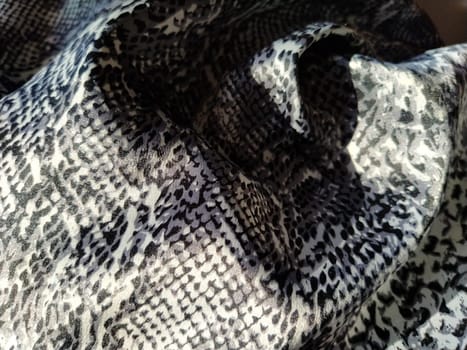Crumpled silk gray spotted fabric. Pleasant shine of fabric, overflow of light is reflected in a piece of textile.