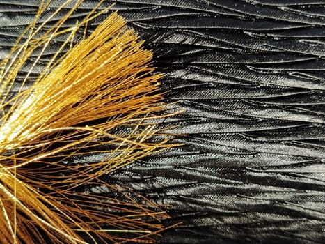 golden tassel on silk black textured fabric. Glitter fabric and silk threads. close-up.