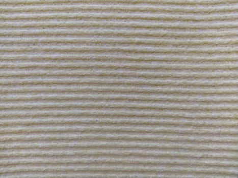 Beige or gray horizontal stripes. Dishwashing sponge or microfiber cloth close up. Soft focus.