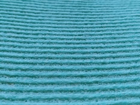 a green or aqua ribbed strip. Dishwashing sponge or microfiber cloth close-up. Soft focus.