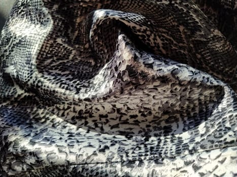 Crumpled silk gray spotted fabric. Pleasant shine of fabric, overflow of light is reflected in a piece of textile