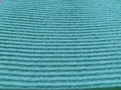 a green or aqua ribbed strip. Dishwashing sponge or microfiber cloth close-up. Soft focus.
