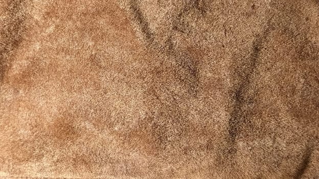 Brown and beige velvet. Close-up. Velvet fabric texture. Irregularities and overflows of light. Deep, rich, chocolate couloured satin. Folded and flowing background.