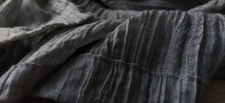 Background of textile texture. Macro. Gray pleated fabric or crumpled textile closeup. Light translucent curtains or tulle in the Scandinavian style. Soft focus