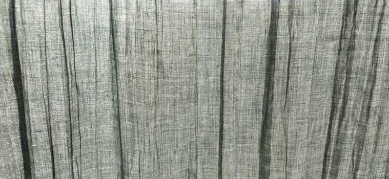 Gray pleated fabric or crumpled textile closeup. Light translucent curtains or tulle in the Scandinavian style. Soft focus. Pastel colors on the fabric