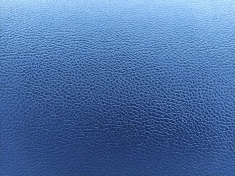 Blue leather background with rich texture. Close-up of artificial gray leather. A blurred background around the edges of the image.