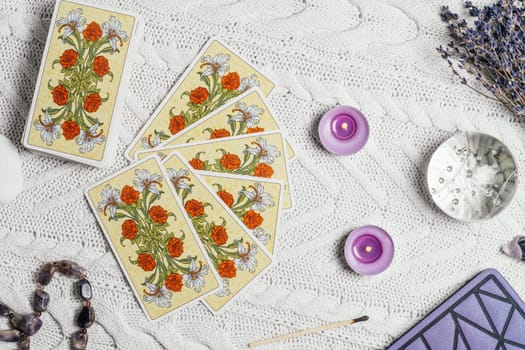 Tarot cards spread face down on white knitted surface with crystal ball, lavender, candles and accessories. Top view. Minsk, Belarus, 11.10.2021