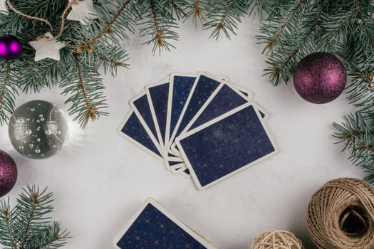 Tarot cards fanned back up on white concrete surface with Christmas tree branches and decorations. Minsk, Belarus, 19.11.2021