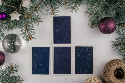 Tarot cards spread on white concrete surface with Christmas tree branches, candles and decorations. Minsk, Belarus, 19.11.2021