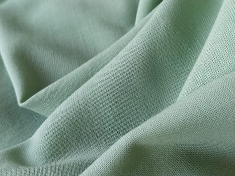 Close up of a woolen fabric of green color. Abstract canvas background, empty template. Thin natural fabric, wool or linen.