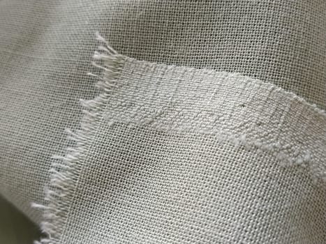 Close up of a woolen fabric of green color. Abstract canvas background, empty template. Thin natural fabric, wool or linen. The edge of the fabric is treated against chapping.