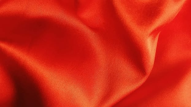 Beautiful scarlet fabric with orange overflow. Shiny silk or satin folded in waves. Modern style. Background for a celebration, ceremony, invitation card, advertising poster. underwear fabric pattern.