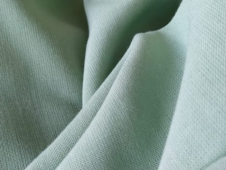 Close up of a woolen fabric of green color. Abstract canvas background, empty template. Thin natural fabric, wool or linen.