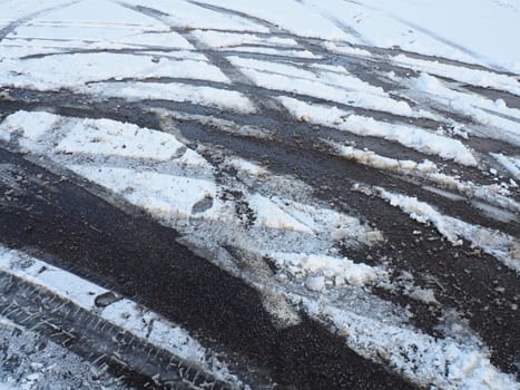 A fork or siding from a roundabout. Snowdrifts on the side of the road. Bad weather and traffic. Snow on asphalt. Difficult driving conditions. Winter slosh on the road. Braking distance of a car.
