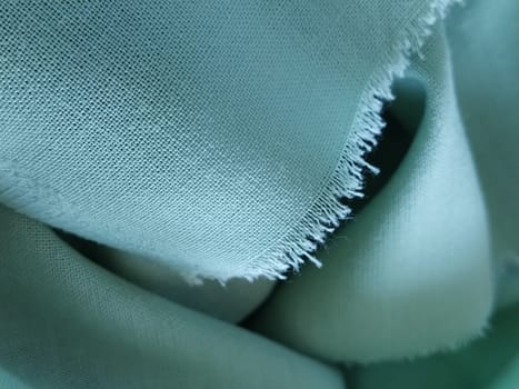 Close up of a woolen fabric of green color. Abstract canvas background, empty template. Thin natural fabric, wool or linen. The edge of the fabric is treated against chapping.
