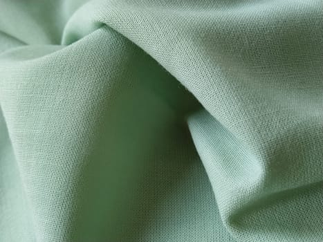 Close up of a woolen fabric of green color. Abstract canvas background, empty template. Thin natural fabric, wool or linen.