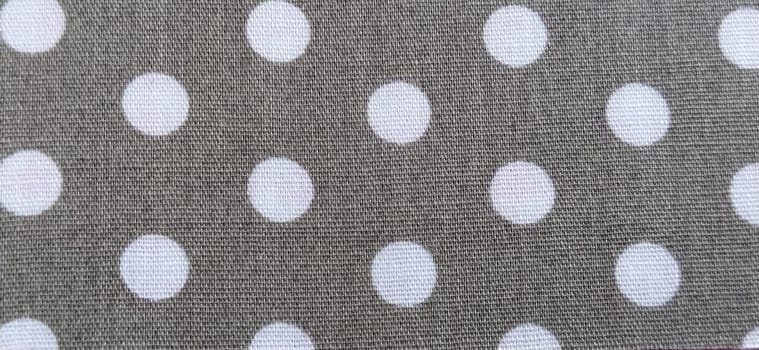 fabric white polka dots on a gray background, smoothed flat surface.