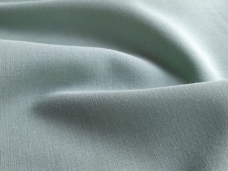Beautifully folded light green fabric. Soft pleasant waves and flounces on textiles. Close-up. Drapery for curtains, fabric for dressmaking or upholstery.