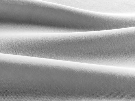 Beautifully horizontally folded fabric. Soft pleasant waves and flounces on textiles. Close-up. Drapery for curtains, fabric for dressmaking or upholstery. Black and white monochrome image