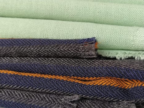 Green and black striped fabrics stacked in a pile. Close-up