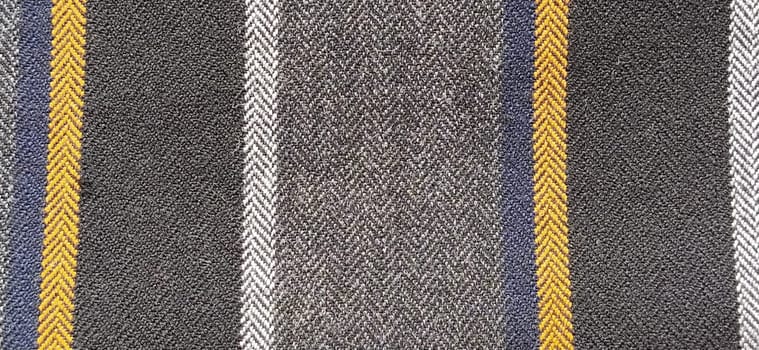 Gray-black fabric with orange and blue stripes. Textile fabric on the surface. Natural wool material for sewing clothes and upholstery. Lifestyle. Close-up. Soft focus.